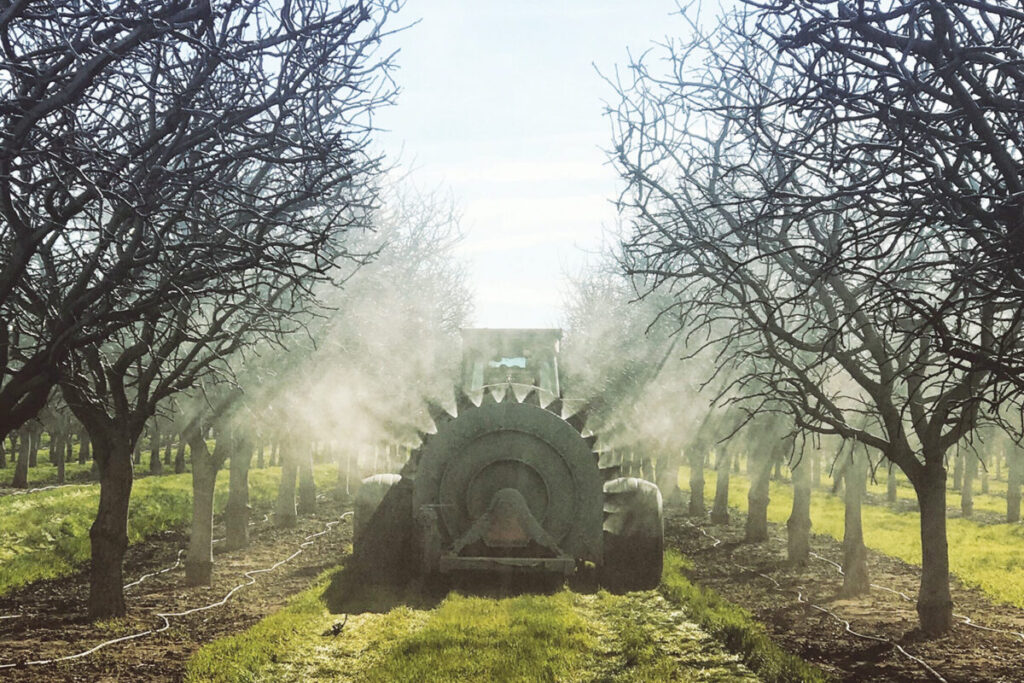 Farm equipment spraying trees in an orchard.