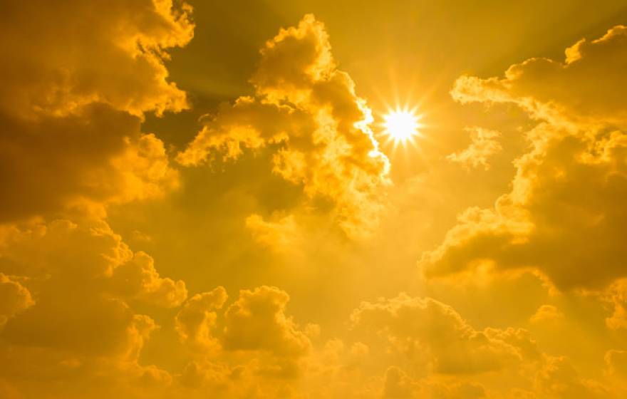 Yellow sky with bright sun and clouds.