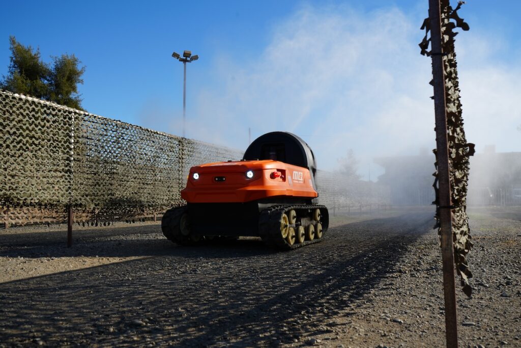 Piece of red robotic ag equipment driving on soil.