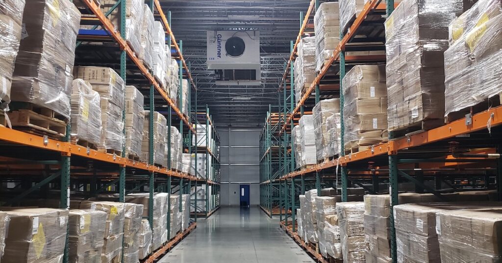 Storage facility with shelves filled with plastic-wrapped boxes.