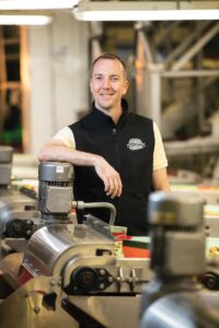 Man standing in front of walnut processing equipment.