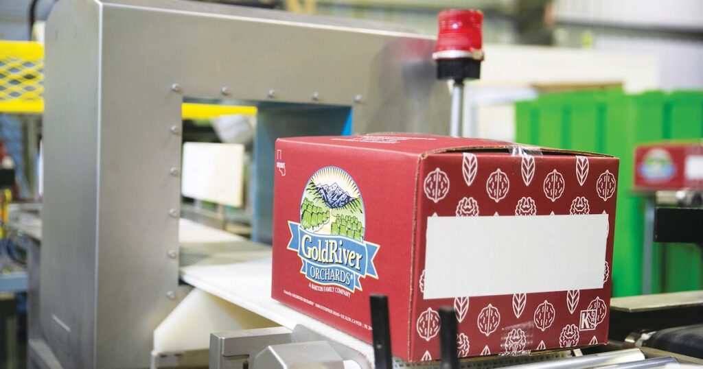 Red GoldRiver Orchards box on a conveyor belt.