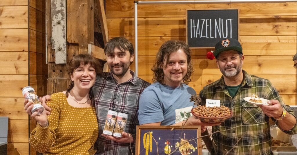 Woman and three men standing together and holding up hazelnut products.