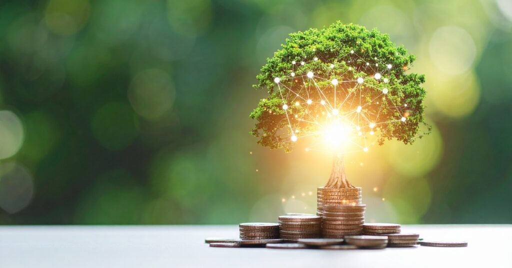 A glowing lightbulb with a thriving tree, sprouts from a foundation of coins.