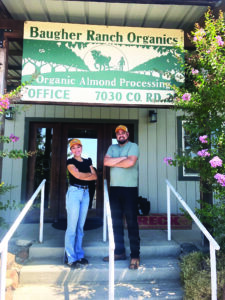 Two employees standing beneath a Baugher Ranch Organics sign.