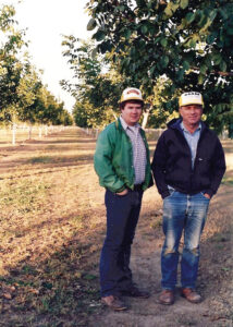 Old photo of Herb and Bill Carrier standing side by side in a walnut orchard.
