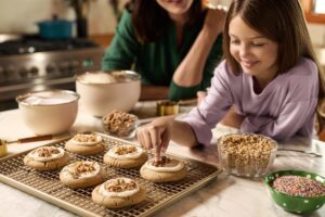 Young girl and woman smiling over baking supplies.