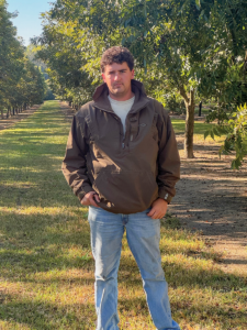 Cole Leger standing in a pecan orchard.