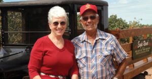 Couple posing and smiling in front of a truck.