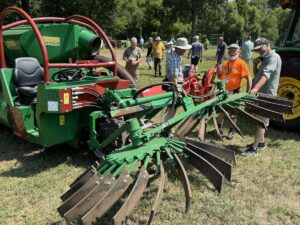 Group of men inspecting farm equipment in a field.