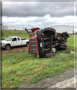 A large truck on its side next to an upright pickup truck.