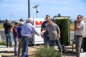 Two men shaking hands in front of MyLand equipment.