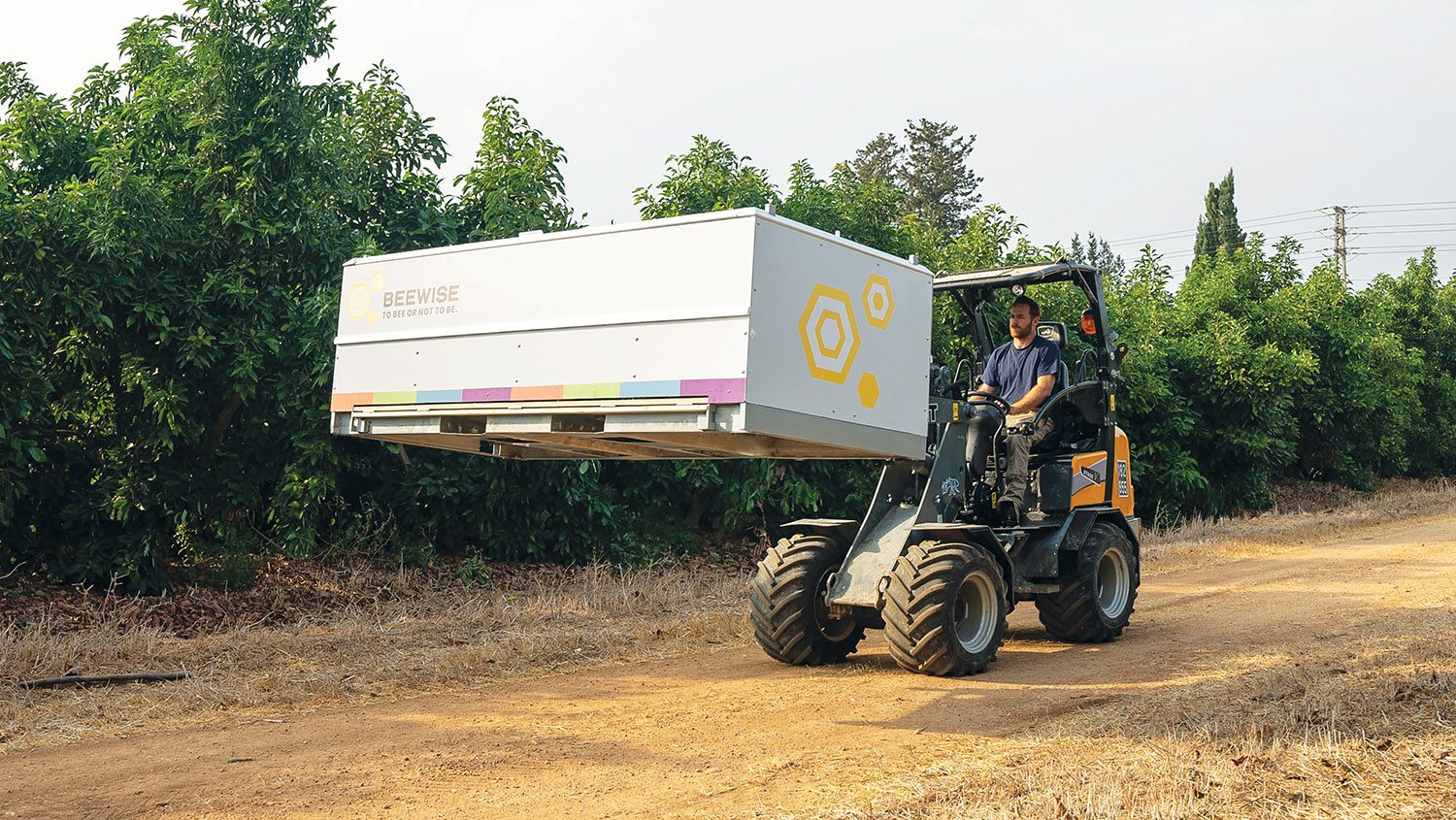 man driving tractor hauling a BeeHome system to monitor hive health