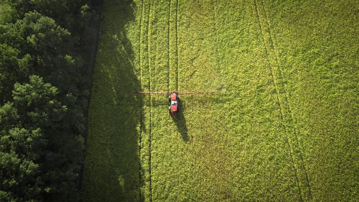 An aerial view of a tractor traversing a green field