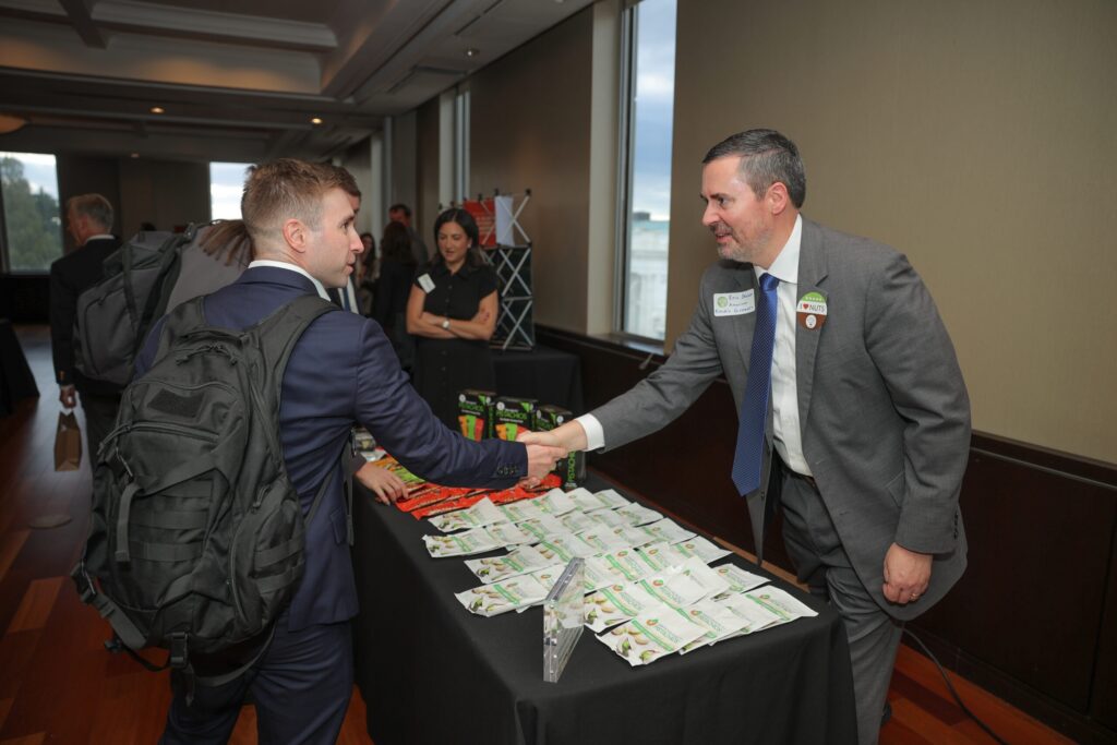 two men shaking hands over a table with informational flyers on it