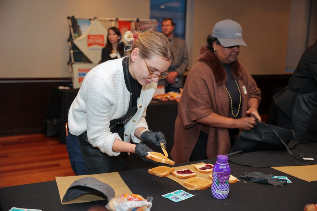 person wearing gloves preparing a peanut butter and jelly sandwich